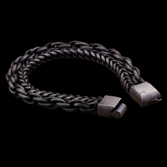 A two-strand gunmetal black bracelet with metal chains, displayed on a wooden surface.