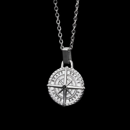 pendant necklace featuring a silver compass design, on a dark background.